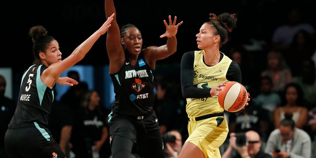 Seattle Storm forward Alysha Clark, right, passes as New York Liberty guard Kia Nurse, left, and center Tina Charles,center, defend during the first half of a WNBA basketball game, Sunday, Aug. 11, 2019, in New York. (AP Photo/Kathy Willens)
