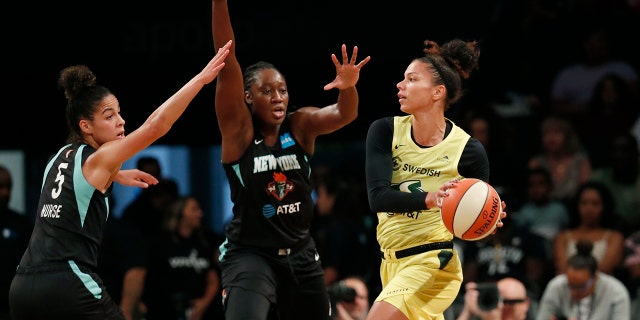 Seattle Storm forward Alysha Clark, right, passes as New York Liberty guard Kia Nurse, left, and center Tina Charles,center, defend during the first half of a WNBA basketball game, Sunday, Aug. 11, 2019, in New York. (AP Photo/Kathy Willens)