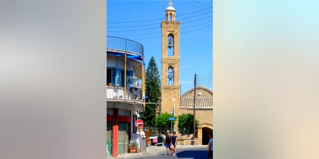 Tourist walk in the old city by a Christian Orthodox church in downtown Nicosia, Cyprus, Thursday, Aug. 1, 2019. Cyprus' attorney general says he has instructed police to launch an investigation into whether an Orthodox Christian bishop has committed a criminal offense over his remarks on homosexuals.