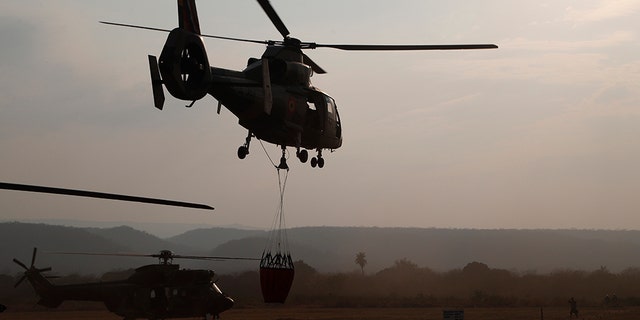 A helicopter lifts off from a military airport Robore, Bolivia, with water to drop on the Chiquitanía Forest as the military fights forest fires, Sunday, Aug. 25, 2019.