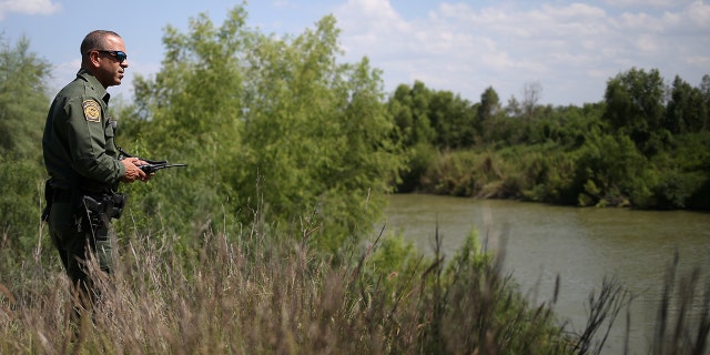 A U.S. Border Patrol agent at the Mexico-U.S. border scans the Rio Grande for rafts near McAllen, Texas, U.S., May 9, 2018.  REUTERS/Loren Elliott - RC12E7ABE080