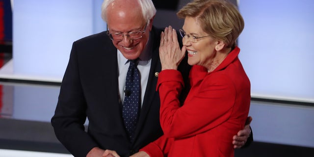 Democratic presidential candidate Sen. Bernie Sanders (I-VT) and Sen. Elizabeth Warren (D-MA) greet each other at the start of the Democratic Presidential Debate at the Fox Theatre in Detroit on July 30, 2019.