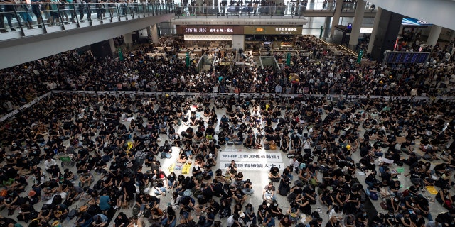 Protesters surround banners that read: "Those on the street today are all warriors!" center top, and "Release all the detainees!" during a sit-in rally at the arrival hall of the Hong Kong International Airport in Hong Kong on Monday.