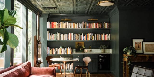 Joanna decided on a library and living room-type setting with dark green walls and eclectic furniture to really punch up her team’s creativity.
