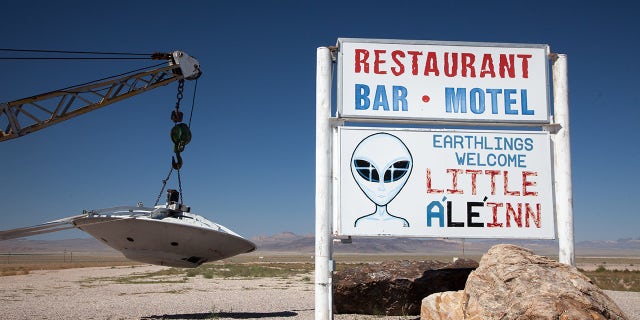 Sign indicating Little A "The Inn" and a flying saucer suspended at a tow truck, Rachel, Nevada, near Area 51.