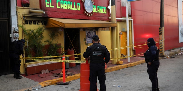 Police officers guard the scene outside a bar where more than 20 people died in an overnight attack, in Coatzacoalcos, Mexico, on Wednesday.