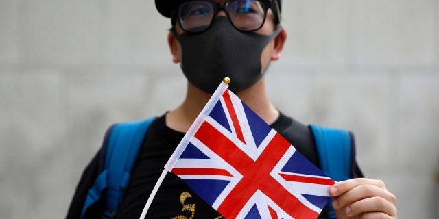 A supporter holds a British flag outside of the British Consulate in Hong Kong during a rally in support of an employee of the consulate who was detained while returning from a trip to China, Wednesday, Aug. 21, 2019.