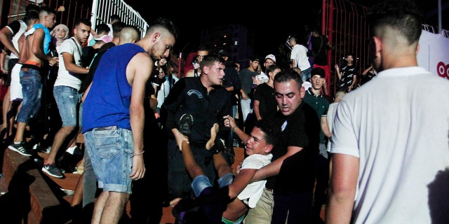 A man is evacuated during a concert by Algerian rap artist Abderraouf Derradji's, known as Soolking, at a stadium in Algiers, Thursday, Aug. 22, 2019. (AP Photo/Fateh Guidoum)
