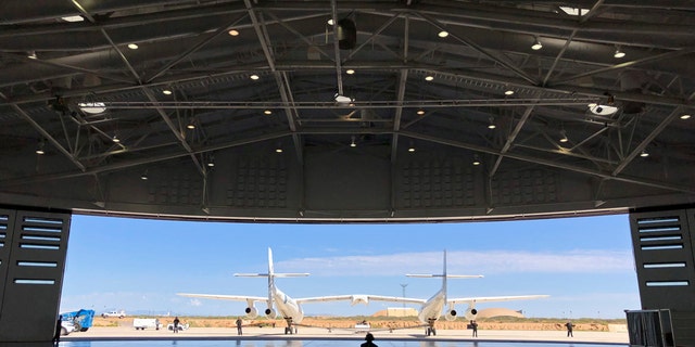 Virgin Galactic ground crew guide the company's carrier plane into the hangar at Spaceport America following a test flight over the desert near Upham, New Mexico, on Thursday, Aug. 15, 2019. The carrier plane is now permanently based at the spaceport after arriving earlier this week. (AP Photo/Susan Montoya Bryan)