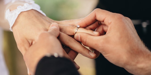Closeup of a groom placing a wedding ring on a bride's hand. "You're spot-on and doing the right thing," one person wrote to the Reddit user who is worried about her plan to step away from the reception during the father-daughter dance.