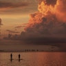 Two paddle boarders stop to watch the sunrise on a stormy morning in Sanibel, Florida, Aug. 15, 2019. 