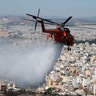 A helicopter drops water over a hill stopping a wildfire in the eastern Athens suburb of Vironas as the ancient Acropolis hill is seen in the background, Aug. 28, 2019. 