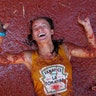 A reveler lies in a puddle of squashed tomatoes during the annual "Tomatina", tomato fight fiesta, in the village of Bunol, near Valencia, Spain, Aug. 28, 2019. 