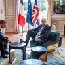 Britain's Prime Minister Boris Johnson places his foot on a table as he talks with French President Emmanuel Macron during their meeting at the Elysee Palace, in Paris, Aug. 22, 2019. 