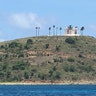 A view of a blue and white building on top of a hill and surrounded by palm trees on Jeffrey Epstein's Little St. James Island. 