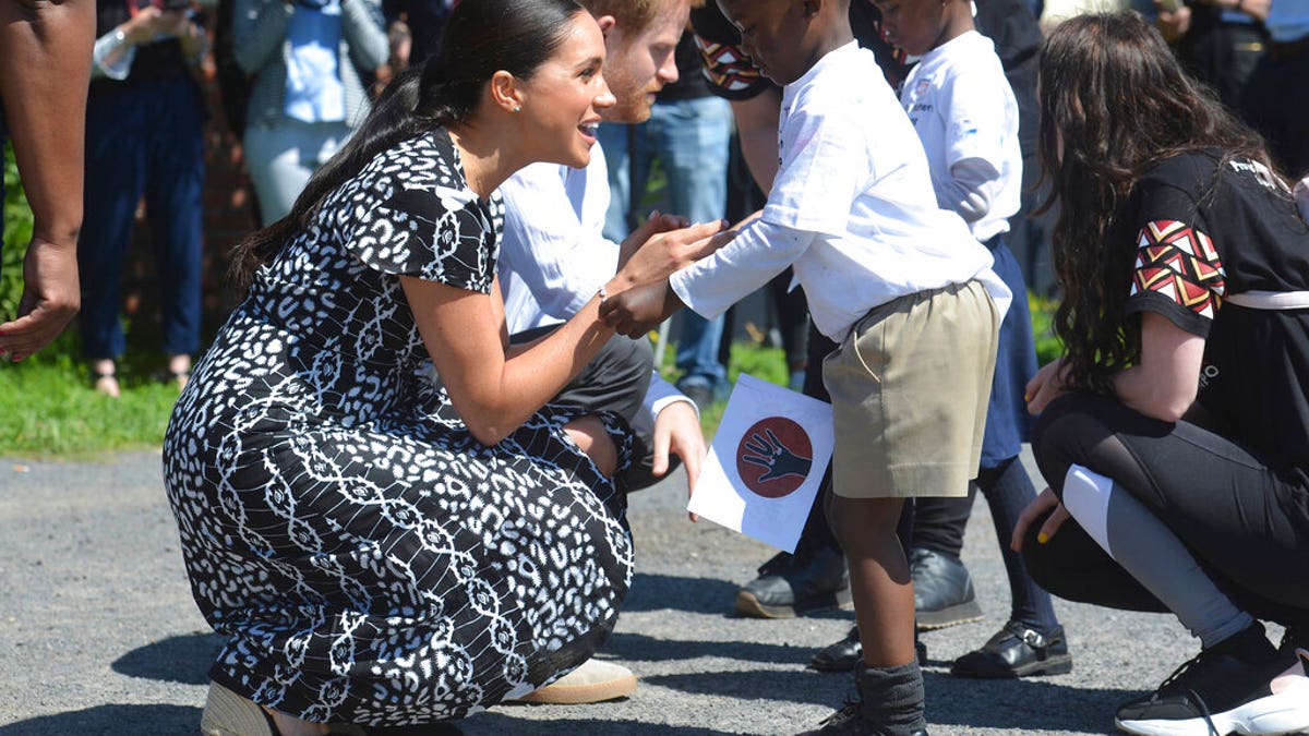 Britain's royal couple Prince Harry and Meghan Duchess of Sussex, greet children on their arrival at the Nyanga Methodist Church in Cape Town, South Africa, Monday, Sept, 23, 2019. It houses a project where children are taught about their rights, self-awareness and safety, and are provided self-defense classes and female empowerment training to young girls in the community. The royal couple are starting their first official tour as a family with their infant son, Archie.