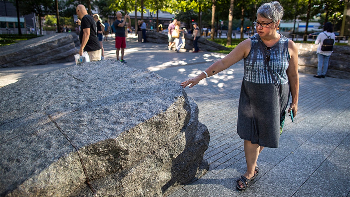A visitor touches one of the granite slabs at the 9/11 Memorial Glade in New York City. When the names of nearly 3,000 Sept. 11 victims are read aloud today at the World Trade Center, a half-dozen stacks of stone will quietly salute an untold number of people who aren’t on the list. (AP)