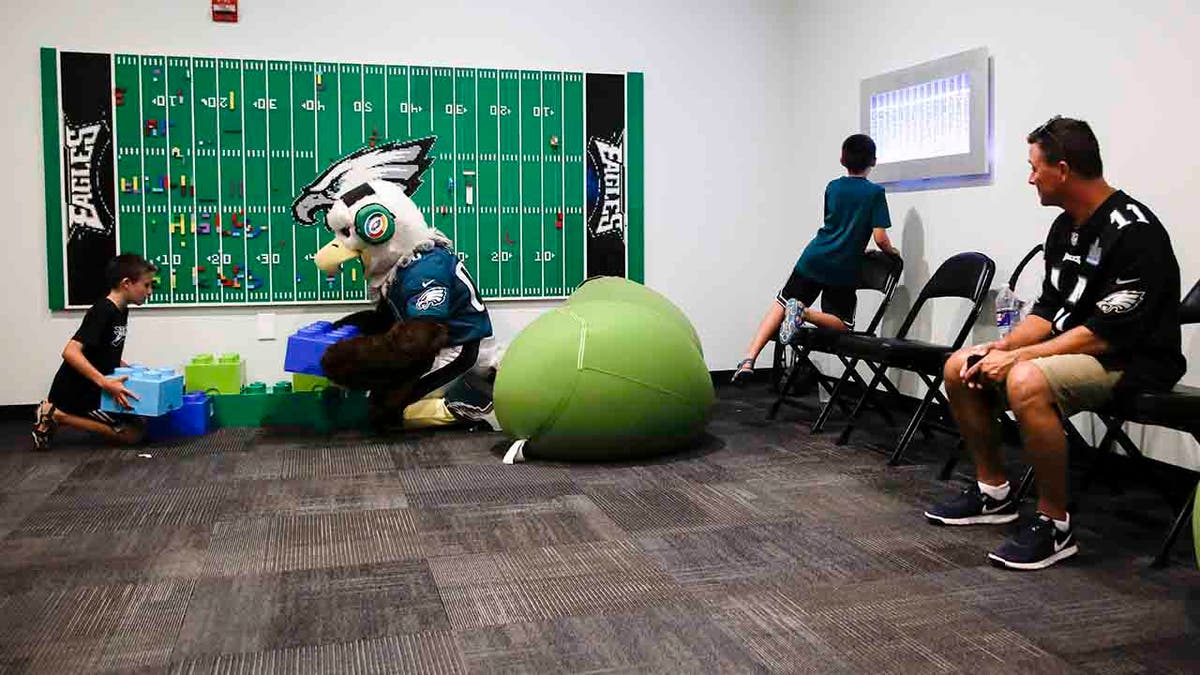 In this Thursday, Aug. 22, 2019, photo, Victor Ykoruk, right, watches as his 10-year-old twin sons, Ryan, left, and Jack, play in the Lincoln Financial Field sensory room, before a preseason NFL football game between the Philadelphia Eagles and the Baltimore Ravens in Philadelphia. (AP Photo/Matt Rourke)