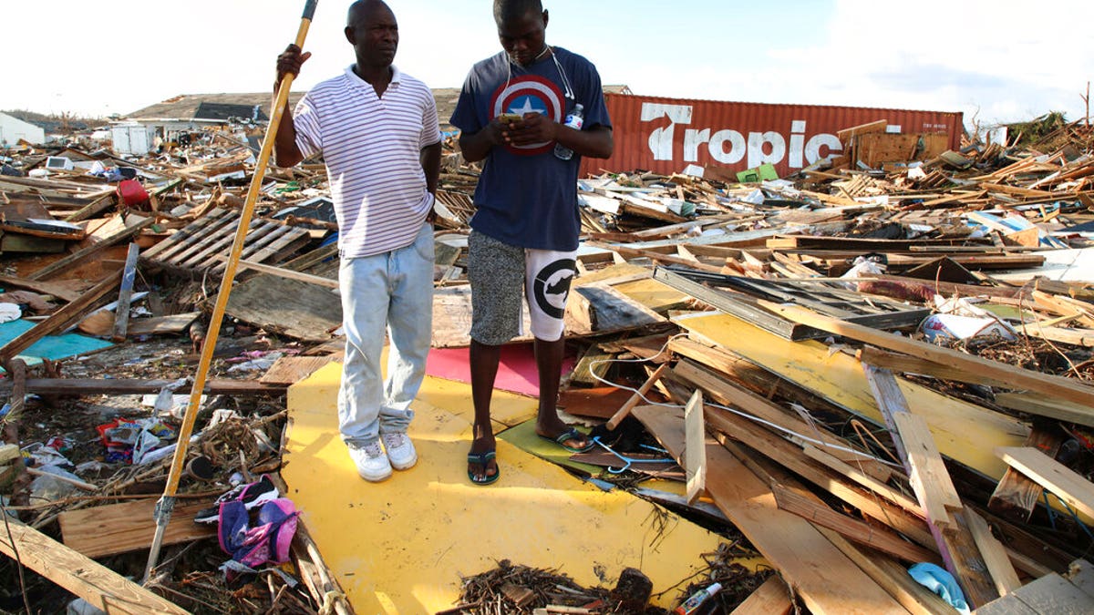 Haitian Burris Filburt, right, and another man stand on the extensive damage and destruction in the aftermath of Hurricane Dorian is seen in The Mudd, Great Abaco, Bahamas, Thursday, Sept. 5, 2019. 