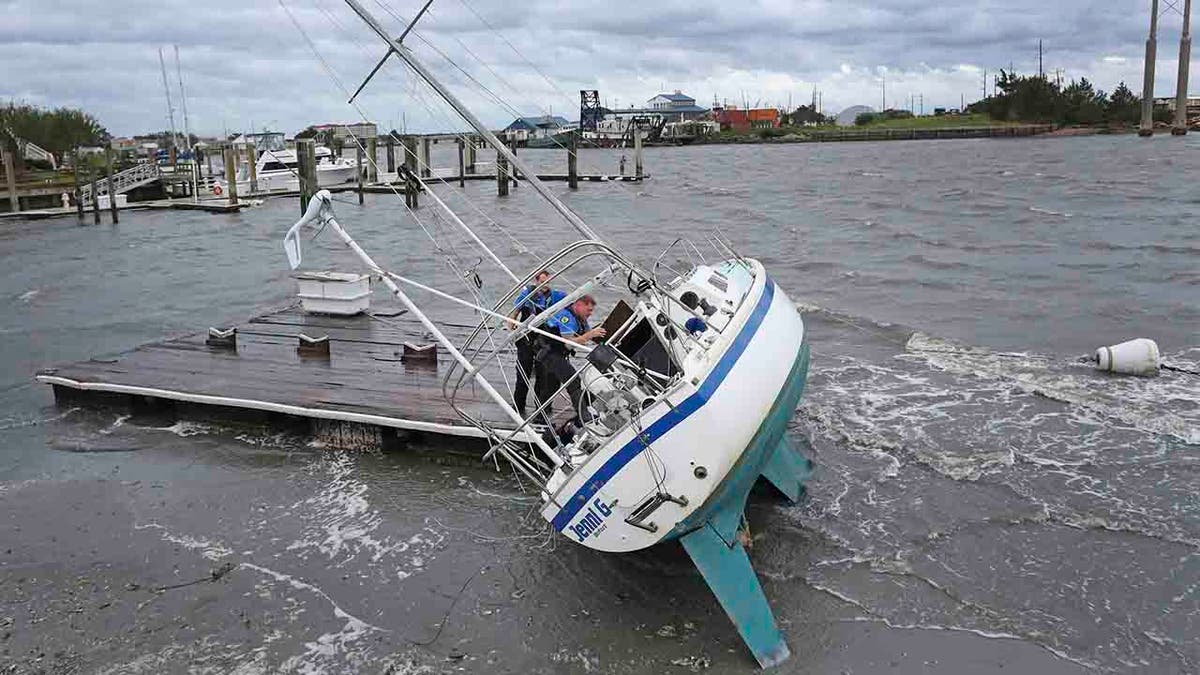 Beaufort Police Officer Curtis Resor, left, and Sgt. Michael Stepehens check a sailboat for occupants in Beaufort, N.C. after Hurricane Dorian passed the North Carolina coast on Friday, Sept. 6, 2019. (AP Photo/Tom Copeland)