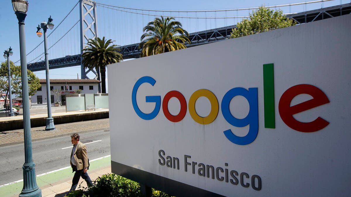 FILE - In this May 1, 2019, file photo a man walks past a Google sign outside with a span of the Bay Bridge at rear in San Francisco. A group of states are expected to announce an investigation into Google on Monday, Sept. 9, to investigate whether the tech company has become too big. (AP Photo/Jeff Chiu, File)