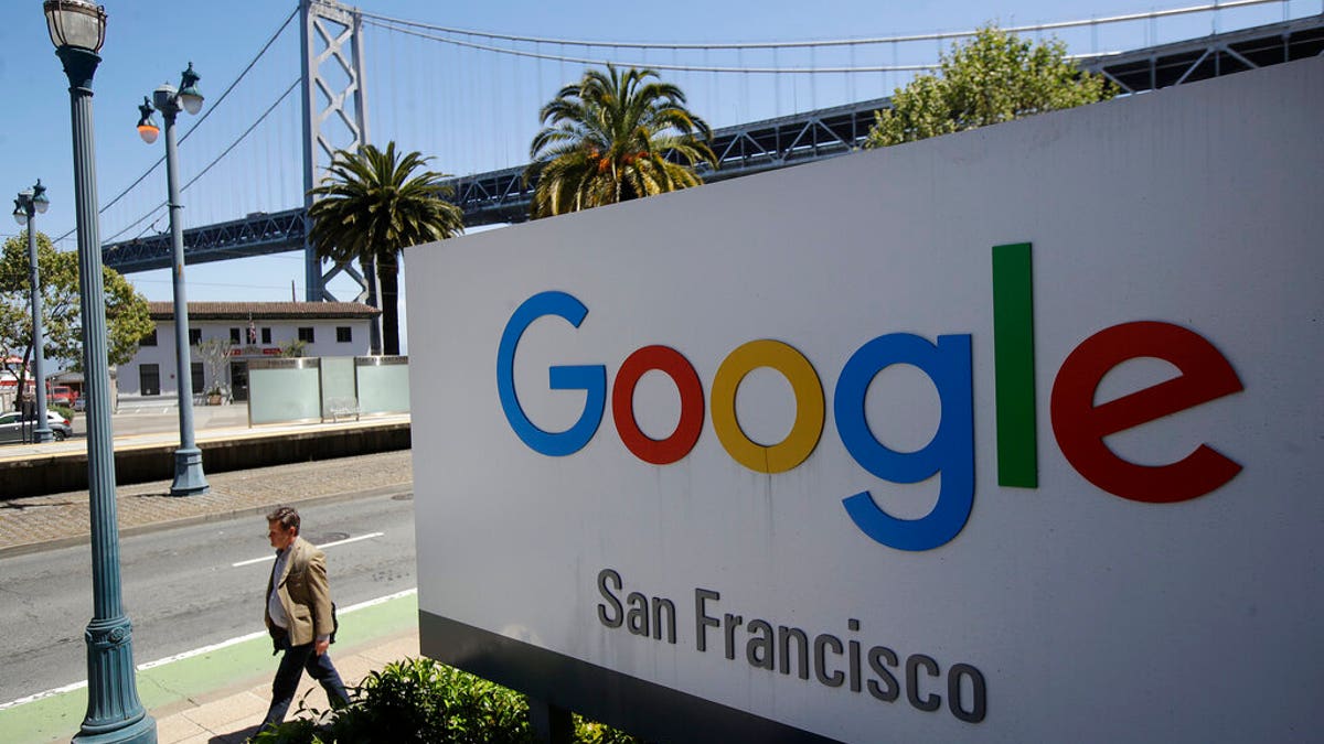 FILE - In this May 1, 2019, file photo a man walks past a Google sign outside with a span of the Bay Bridge at rear in San Francisco. A group of states are expected to announce an investigation into Google on Monday, Sept. 9, to investigate whether the tech company has become too big. (AP Photo/Jeff Chiu, File)