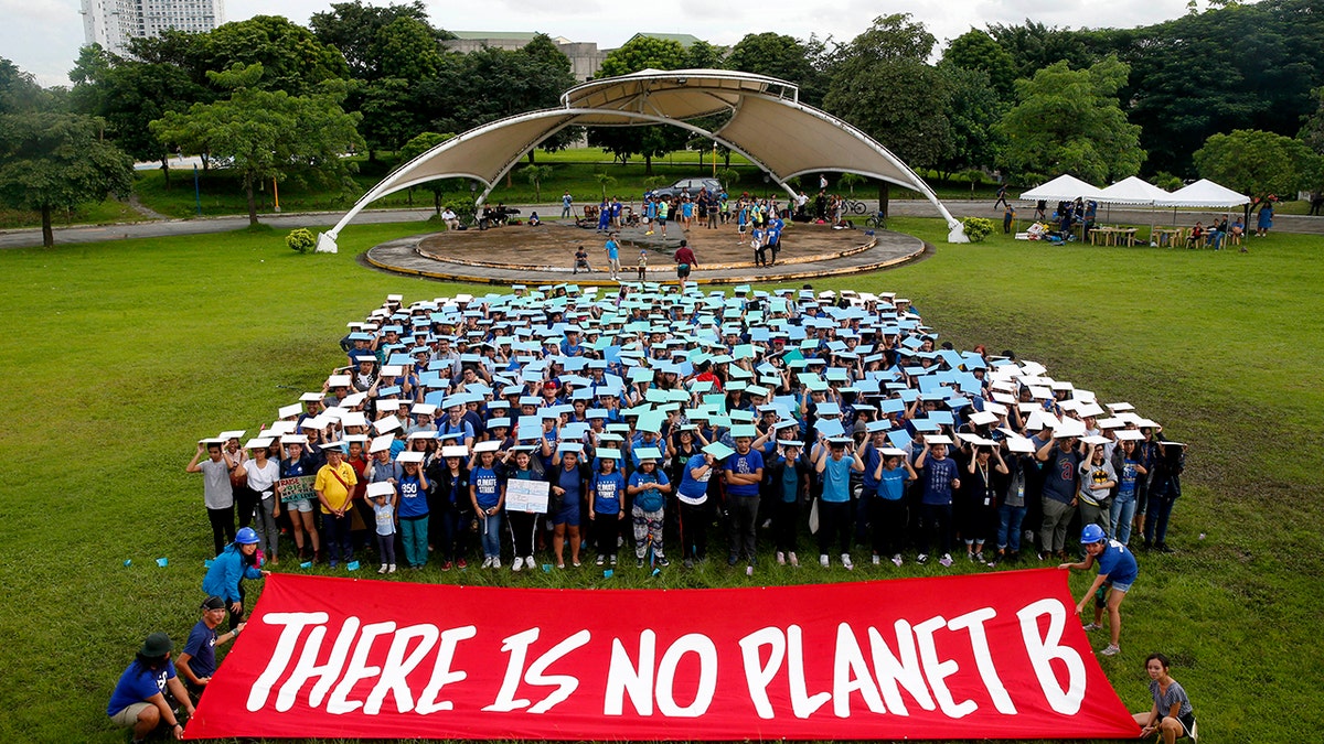 Environmental activists, mostly students, display their message in front of "a human globe" formation to coincide with the global protests on climate change Friday, Sept. 20, 2019, at the University of Philippines campus in suburban Quezon city northeast of Manila, Philippines. Various environmental groups in the country are participating in what is expected to be the world's largest mobilization on climate change known as "Global Climate Strikes." 