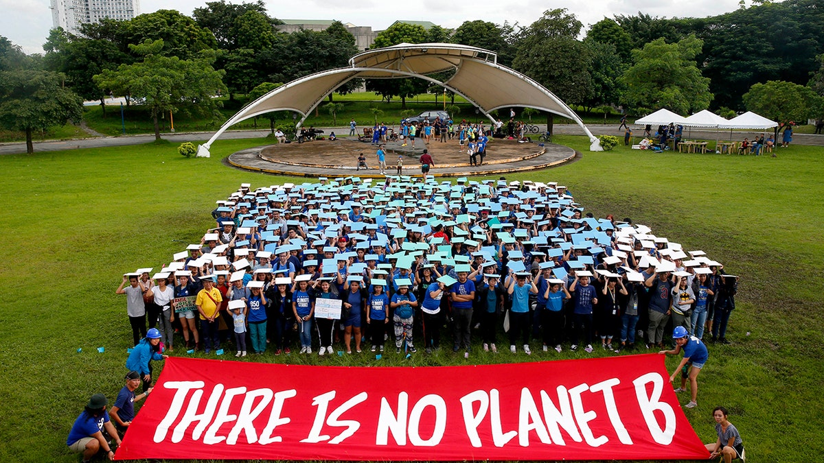 Environmental activists, mostly students, display their message in front of "a human globe" formation to coincide with the global protests on climate change Friday, Sept. 20, 2019, at the University of Philippines campus in suburban Quezon city northeast of Manila, Philippines. Various environmental groups in the country are participating in what is expected to be the world's largest mobilization on climate change known as "Global Climate Strikes."