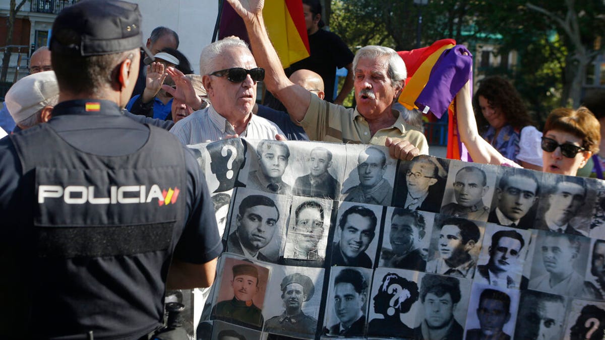 Protesters shout behind a banner showing photos of Spanish Civil War victims, outside the Supreme Court in Madrid, Spain, Tuesday, Sept. 24, 2019. 