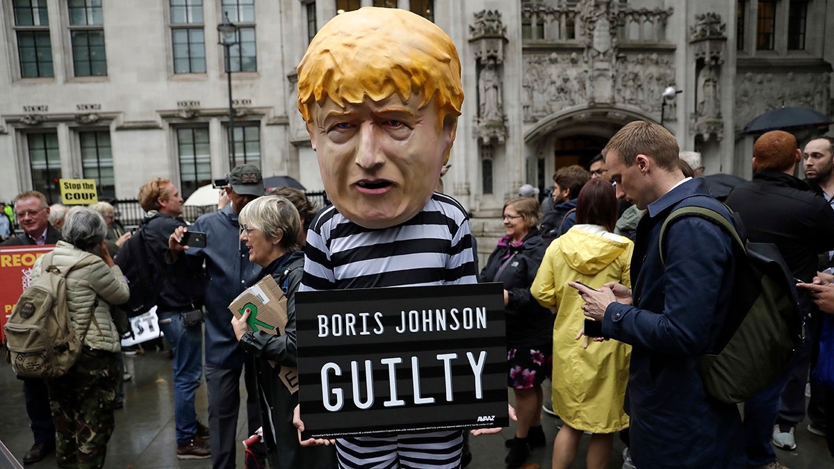 A person dressed as a caricature of British Prime Minister Boris Johnson in a prison uniform stands outside the Supreme Court in London, Tuesday, Sept. 24, 2019. (AP Photo/Matt Dunham)
