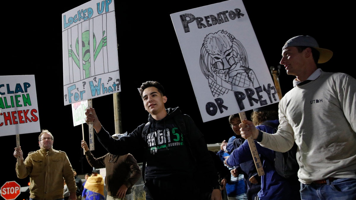 People hold signs at an entrance to the Nevada Test and Training Range near Area 51 Friday, Sept. 20, 2019, near Rachel, Nev. (AP Photo/John Locher)