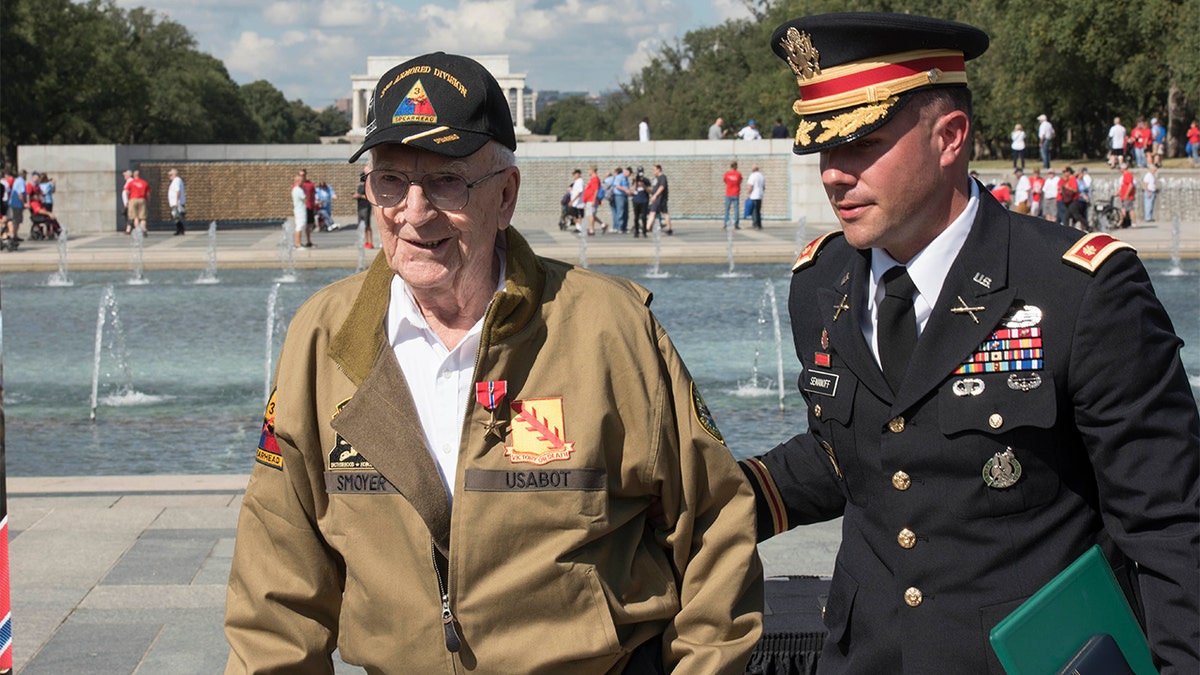 U.S. Army Major Peter Semanoff guides Clarence Smoyer back to his seat after awarding him the Bronze Star at the National WWII Memorial in Washington, D.C. (DoD photo by U.S. Navy Petty Officer 2nd Class James K. Lee)