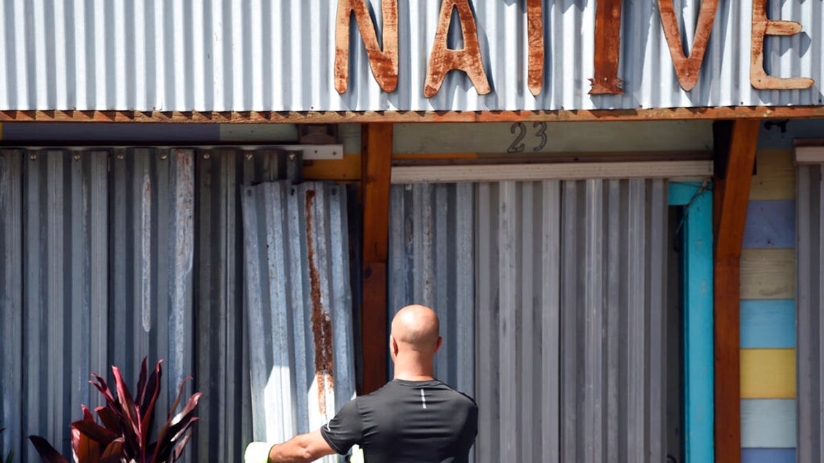 A worker affixes corrugated metal to the front of a business along the main drag in Folly Beach, S.C., on Tuesday, Sept. 3, 2019. Businesses and residents throughout the Charleston area continued to prepare structures for the arrival of Hurricane Dorian as the storm battered the Bahamas with life-threatening storm surge. (AP Photo/Meg Kinnard)