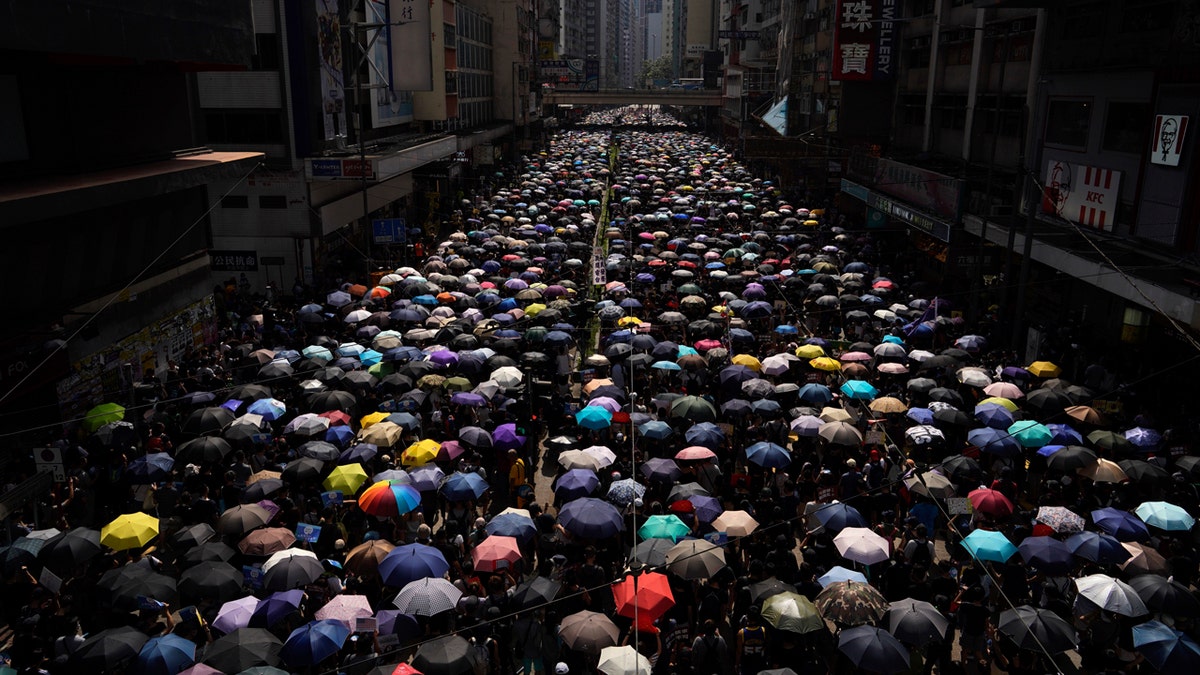 Thousands of Hong Kong people chanted slogans and marched Sunday at a downtown shopping district in defiance of a police ban.