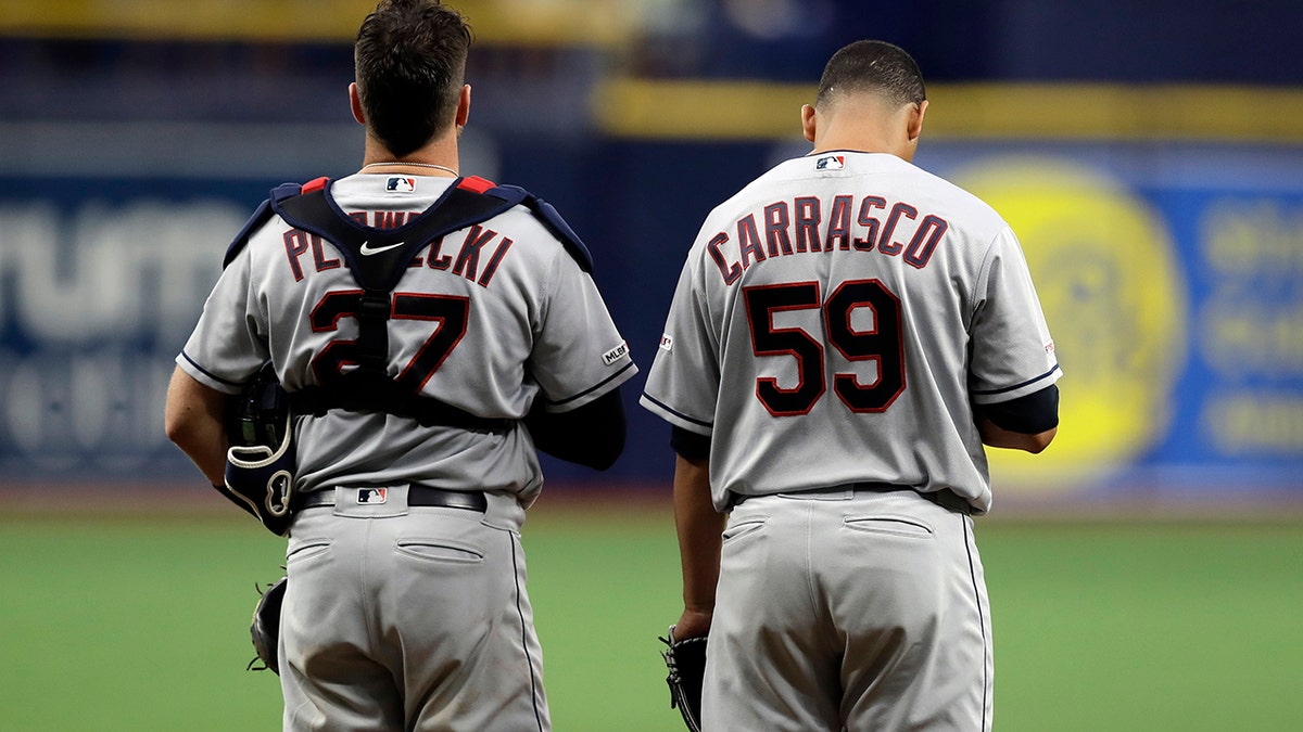 Cleveland Indians pitcher Carlos Carrasco (59) stands with catcher Kevin Plawecki during the playing of "God Bless America" in the seventh inning of a baseball game against the Tampa Bay Rays, Sunday, Sept. 1, 2019, in St. Petersburg, Fla. Carrasco is making his first appearance since May, when he was diagnosed with leukemia. (AP Photo/Chris O'Meara)
