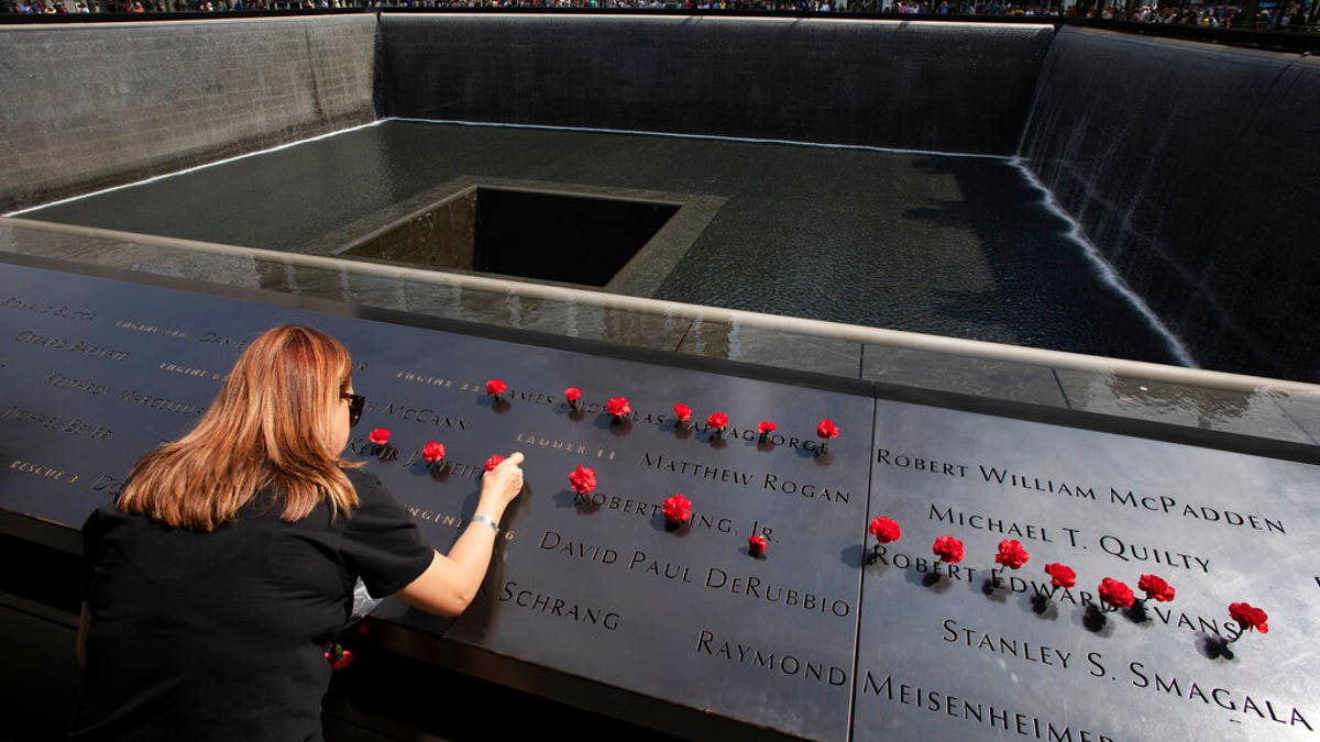 Norma Molina, of San Antonio, Texas, leaves flowers by the names of firefighters from Engine 33 at the September 11 Memorial, Monday, Sept. 9, 2019, in New York. Her boyfriend Robert Edward Evans, a member of Engine 33, was killed in the north tower of the World Trade Center on Sept. 11, 2001. (AP Photo/Mark Lennihan)