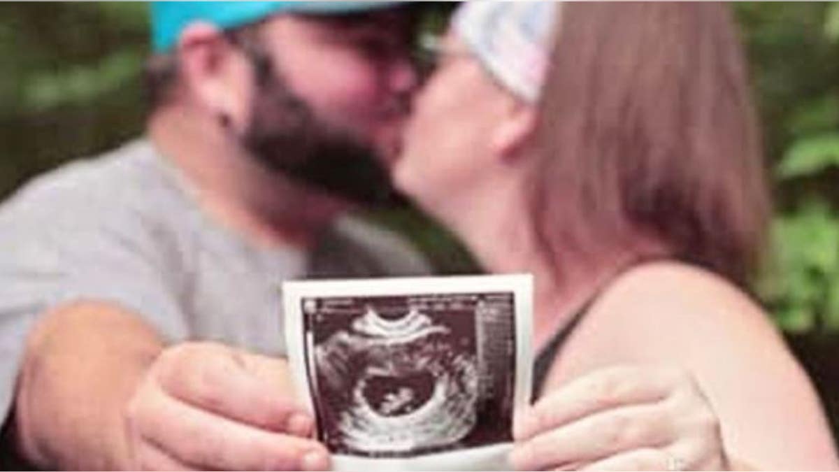 Elisha and Tyler Hessel, showing an ultrasound of their unborn daughter.