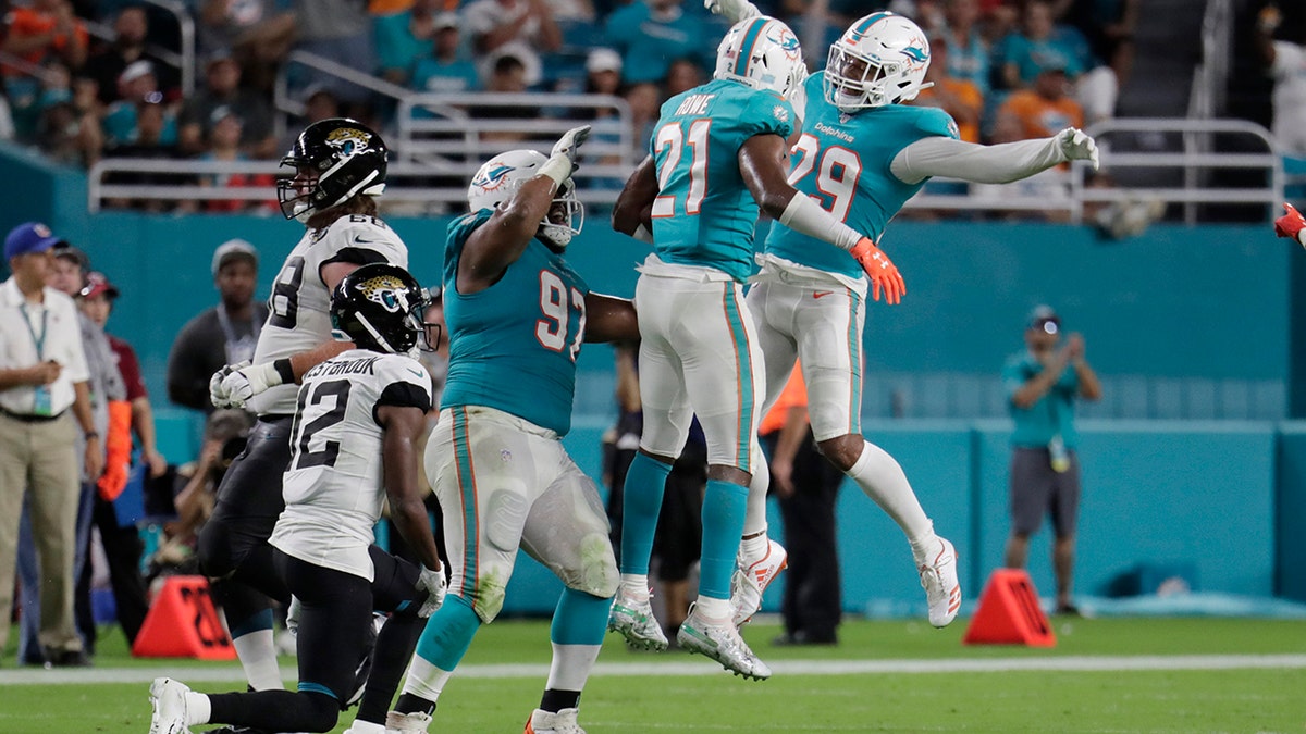 Miami Dolphins cornerback Eric Rowe (21), safety Minkah Fitzpatrick (29) and defensive tackle Christian Wilkins (97) celebrate an interception during the first half of an NFL football preseason game against the Jacksonville Jaguars on Aug. 22, 2019, in Miami Gardens, Fla. (AP Photo/Lynne Sladky)