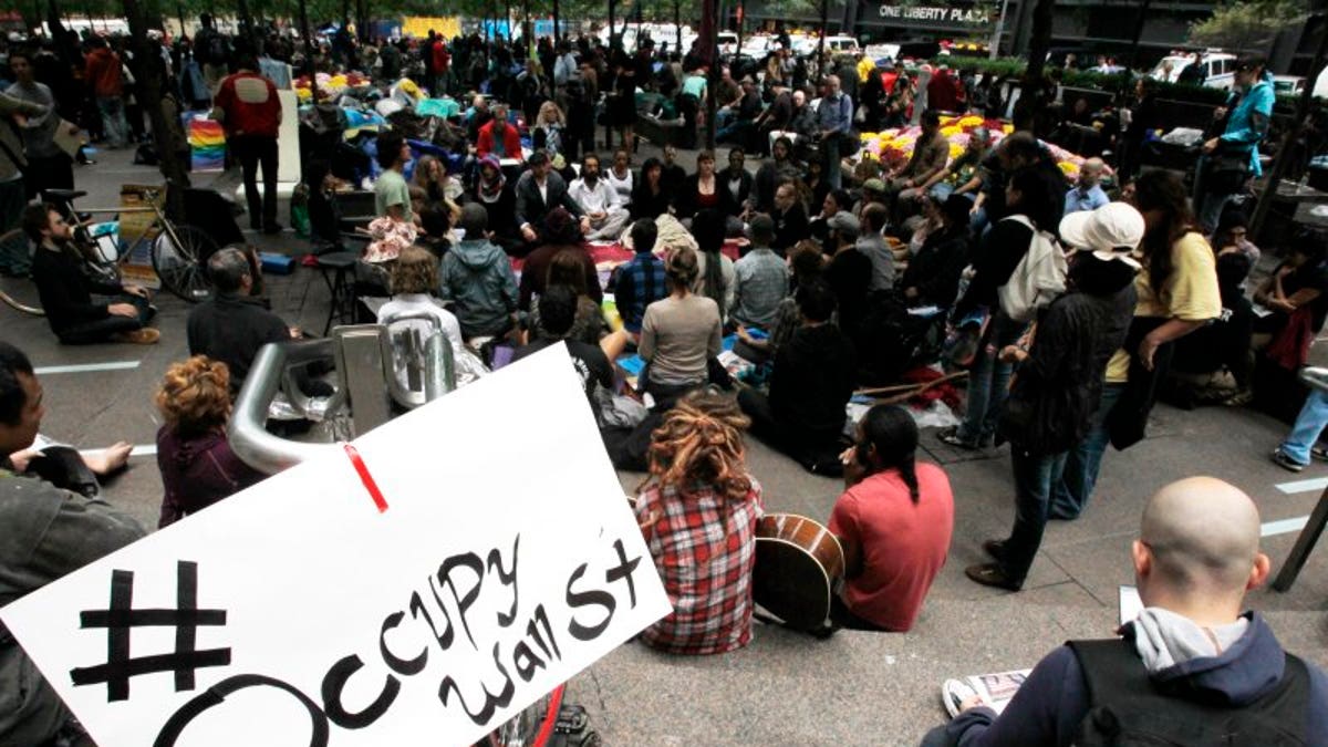 FILE – Occupy Wall Street protesters meditate while a sign bearing their twitter handle hangs from a railing in Zuccotti Park in New York October 1, 2011. REUTERS/Jessica Rinaldi