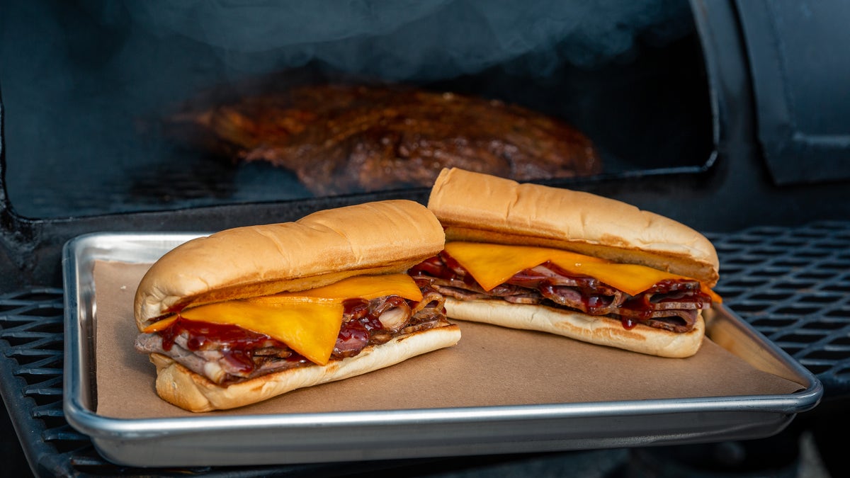 The pit-smoked brisket sandwich is stacked with brisket that is slow-smoked for at least 13-hours before being topped with smoked cheese and barbecue sauce.
