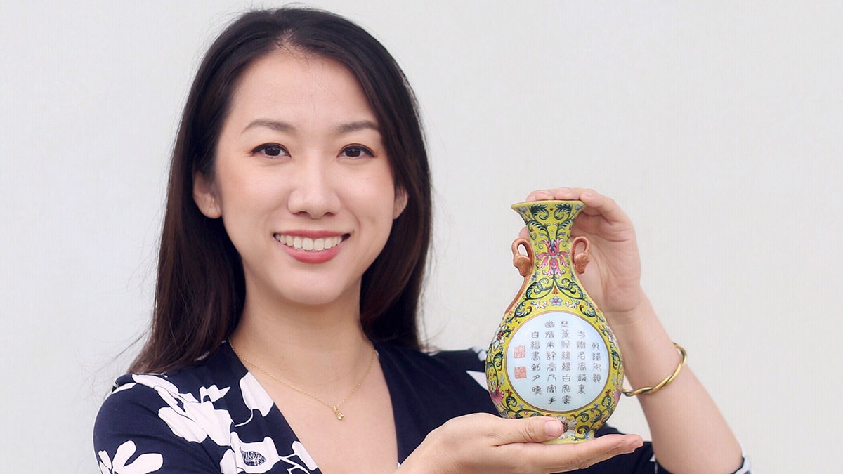 Sworders expert Yexue Li holding the vase, which was bought for £1 in a charity shop. (Credit: Sworders/BNPS)
