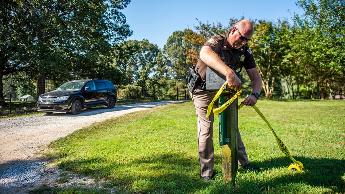 Limestone County Sheriff Sgt. Jonathan Hardiman adding caution tape at the scene of the shooting Tuesday. (Dan Busey/The Decatur Daily via AP)