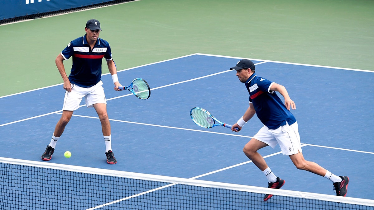 Mike Bryan, left, returns a shot as his brother Bob Bryan, looks on during a first round doubles match against Hubert Hurkacz, of Poland, and Vasek Pospisil, of Canada, at the US Open tennis championships Friday, Aug. 30, 2019, in New York.