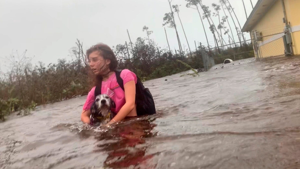 Julia Aylen wades through waist deep water carrying her pet dog as she is rescued from her flooded home during Hurricane Dorian in Freeport, Bahamas, Tuesday, Sept. 3, 2019.