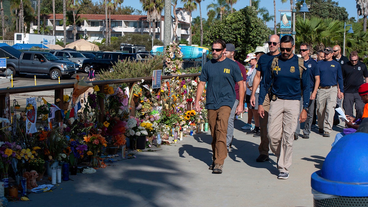 FBI agents walk past a memorial for the victims of the Conception dive boat on the Santa Barbara Harbor, as authorities issue a search warrant for the Truth Aquatics' offices in Santa Barbara, Calif., Sunday, Sept. 8, 2019.  (AP Photo/Christian Monterrosa)