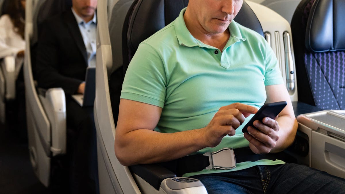 Man traveling by plane and using his cell phone onboard