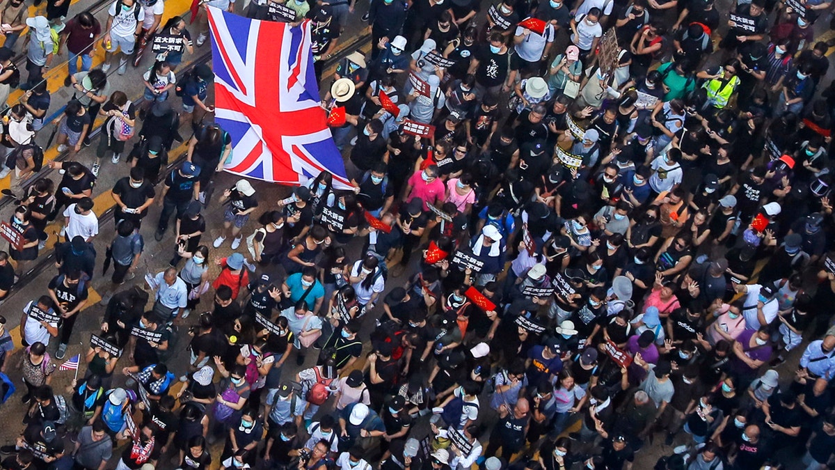 Protesters carry a British flag gather at a shopping district during a rally in Hong Kong, Sunday, Sept. 15, 2019.