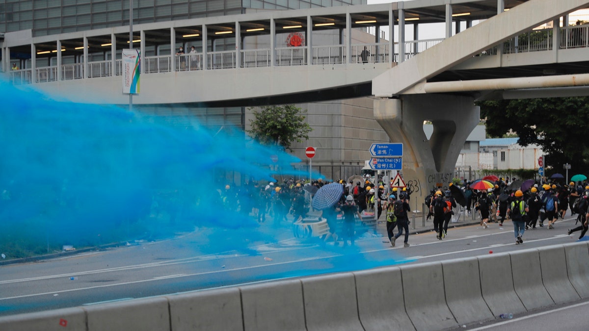A police vehicle sprays blue-colored water towards anti-government protesters during a demonstration near Central Government Complex in Hong Kong, Sunday, Sept. 15, 2019.