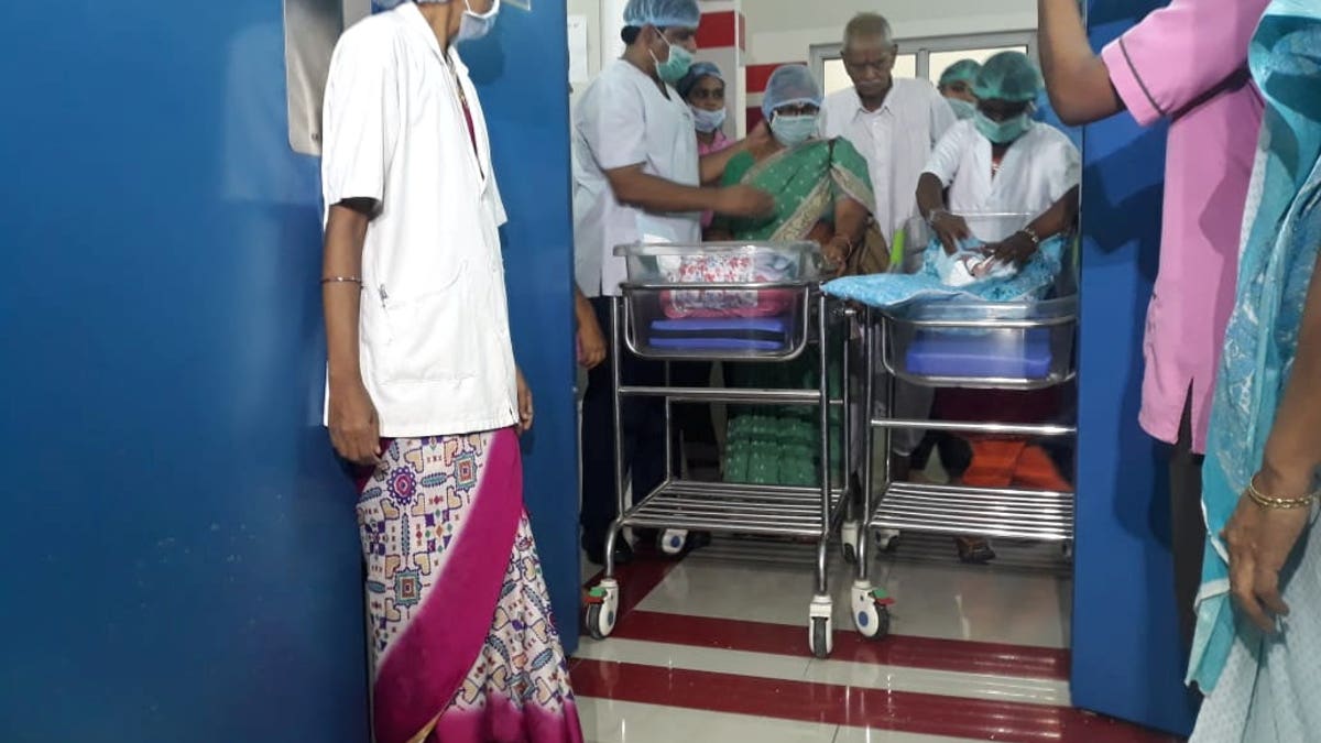 Hospital staff watch as proud dad Rajarao Mangayamma brings his new born twins to a press conference in India.