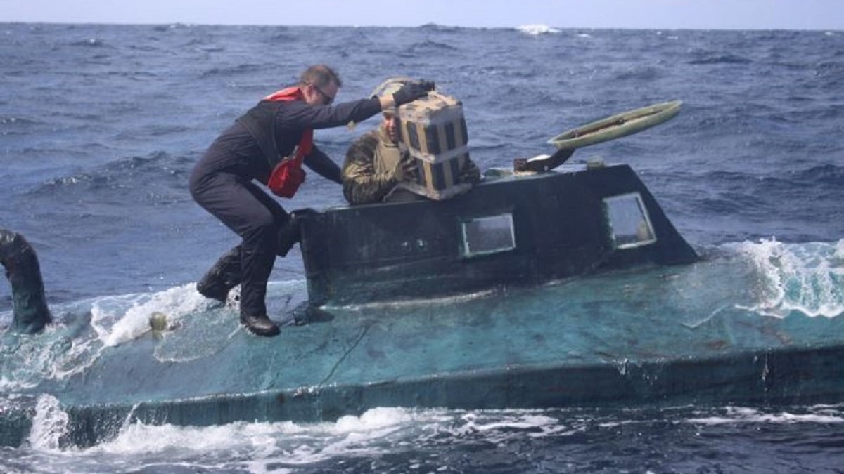U.S. Coast Guard boarding team members climb aboard the suspected smuggling vessel